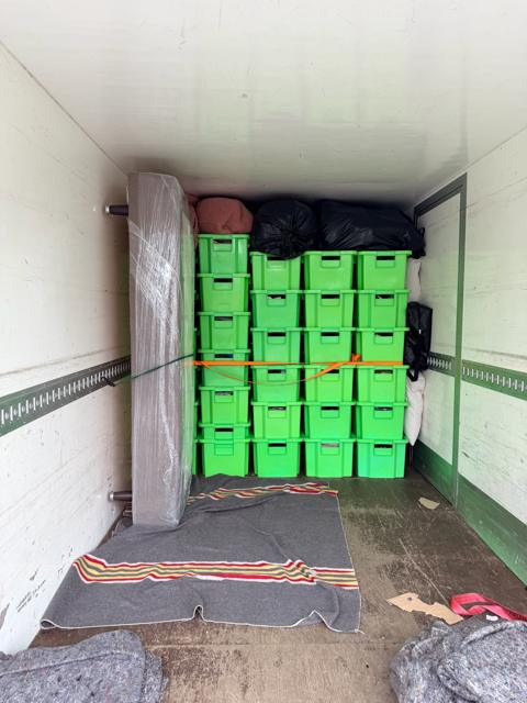 The finished load on the Vaasa to Helsinki move: green moving boxes stacked and strapped inside the truck, a mattress as padding