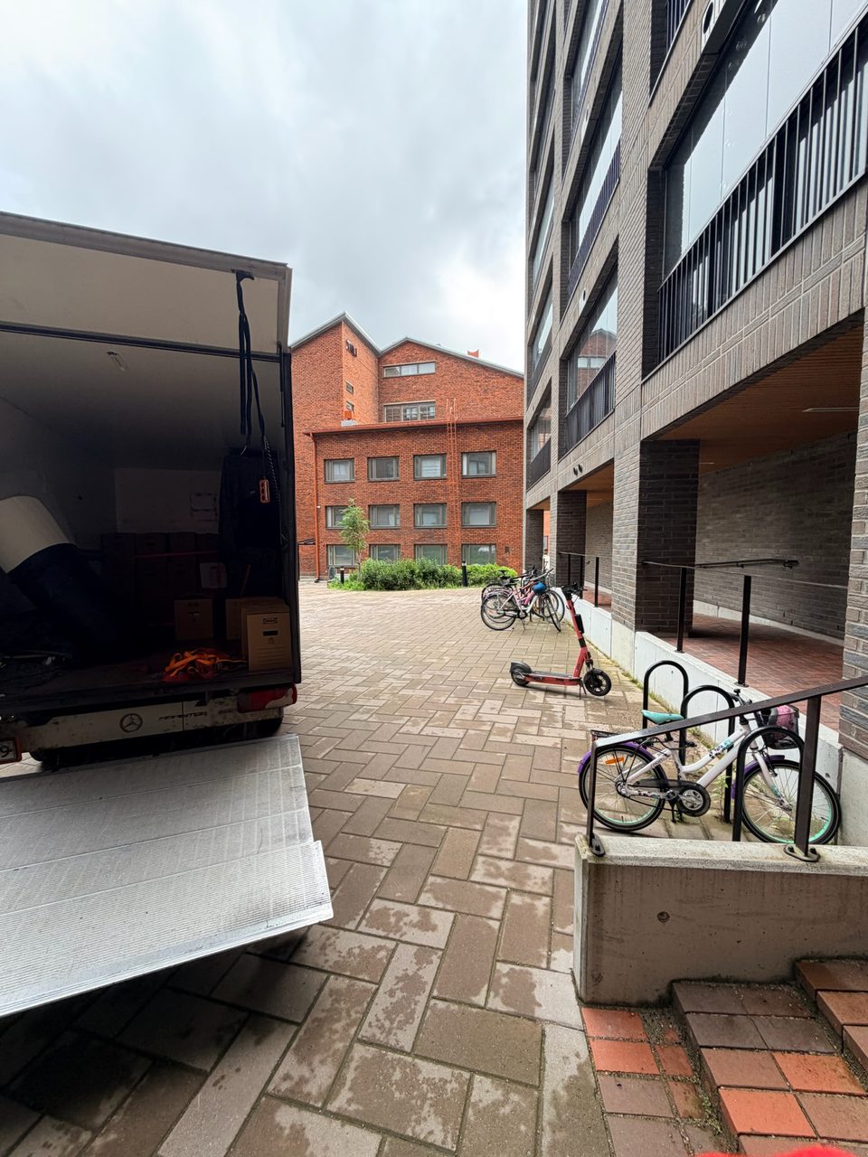 Muuttoauto lastattavana ahtaalla sisäpihalla, IKEA-laatikot kyydissä